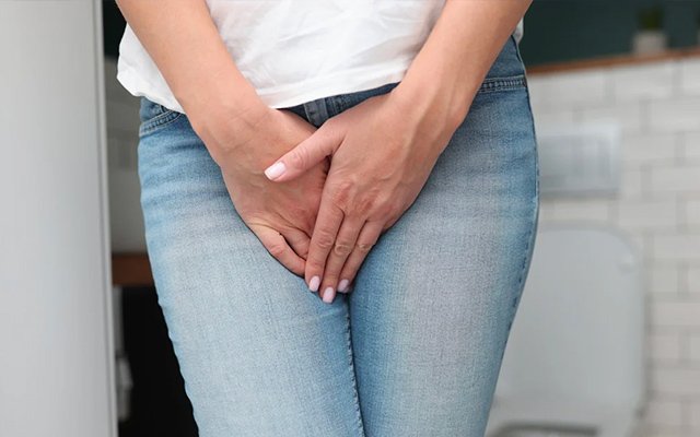 Close-up of a woman clutching her pelvic area indicating urinary discomfort, representing common UTI symptoms